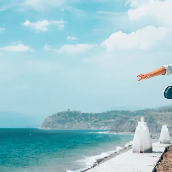 voiture-face-à-la-mer-avec-une-femme-qui-tend-les-bras
