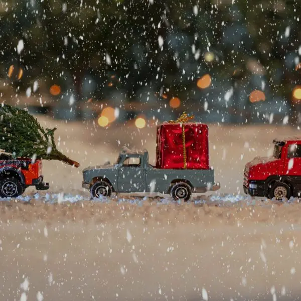 trois petites voitures sous la neige avec des décorations de Noël